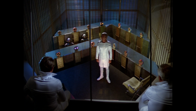 Dr. Elias Huer presents Col. Wilma Deering's plan to verify William "Buck" Rogers's alibi to the Computer Council (BR25: Film, "Awakening").