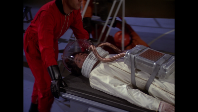 Regis Saroyan in a sick suit, being conveyed on a stretcher to a Thunderfighter (BR25: "Planet of the Slave Girls").
