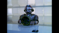 [Photo 1B]: Twiki places Theopolis on a different desk in this shot at Rogers' first debriefing (BR25: Film, "Awakening").
